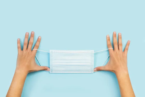 Woman Hands Holding Surgical Mask Light Blue Background Top View — Stock Photo, Image