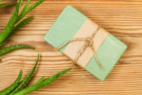 Aloe vera bitkisi olan yeşil sabun. Ahşap bir masanın üstünde.