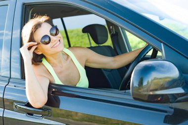 Onun araba sürüş sırasında gülümseyen güzel kadın sürücü.