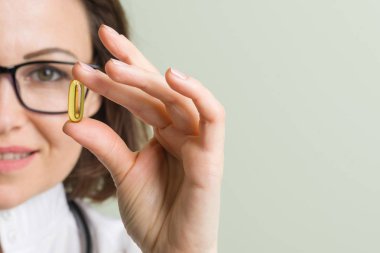 Kadın doktor vitamini kapsülü alır. Sağlıklı yaşam tarzı, beslenme takviyeleri, vitamin d, e, balık yağı kapsülleri.