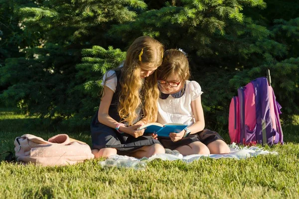 两个小女孩朋友在公园的草地上学习 儿童背包 笔记本 — 图库照片