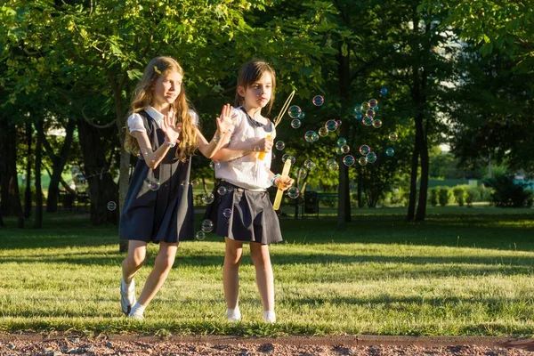 两个小女孩的朋友女生7 岁在公园的草地上玩肥皂泡 — 图库照片