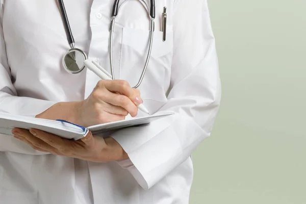 Medical Doctor Woman Stethoscope Taking Notes Her Notepad Green Background — Stock Photo, Image