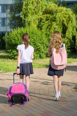 Arkadan Görünüş iki kız öğrenci kız İlköğretim Okulu öğrencilerinin okul çantası bahçedeki ile yürüme.