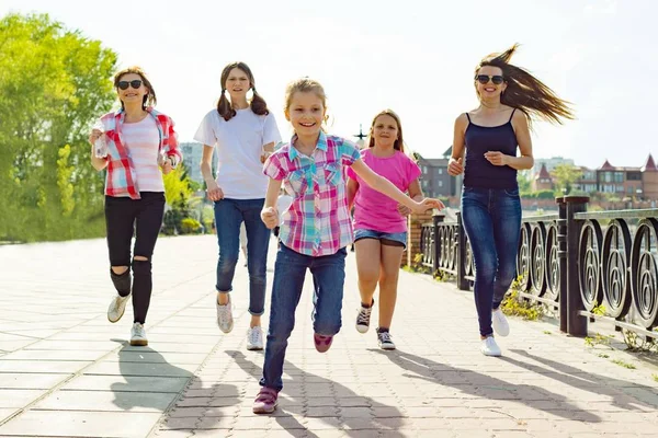 Group of mothers and daughters are running along the road in the park. Urban background.