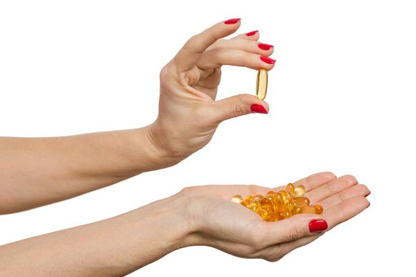 Isolated hand holding capsule of Omega 3 on white background.