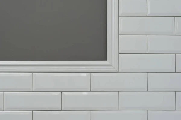 グレーに塗られた壁 壁の一部がタイル覆われた小さな白い光沢のあるレンガ 装飾的なセラミックの成形のタイル 複雑なコーナーの詳細 トイレ 台所の壁の断片 — ストック写真
