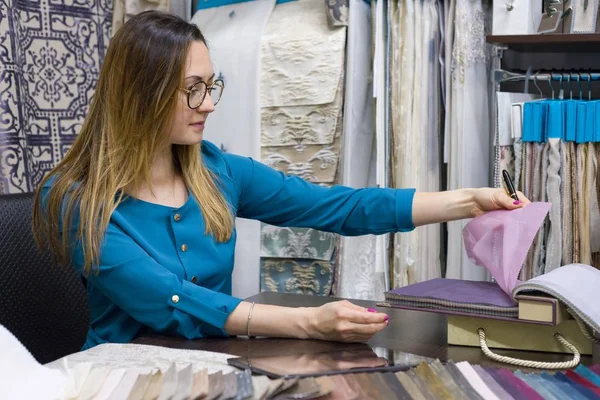 Woman owns a store of interior fabrics and decor works with samples of materials. Small business home textile shop