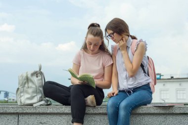 İki kız öğrenciler sırt çantaları ve ders kitapları açık bir parkta ile öğrenme