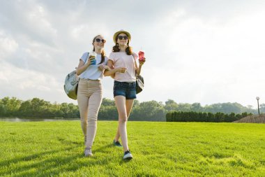 Kız arkadaşlar doğa parkında yürüyüş mesafesindedir. Kızlar yürüyüş boyunca yeşil çim, konuşma, iyi eğlenceler