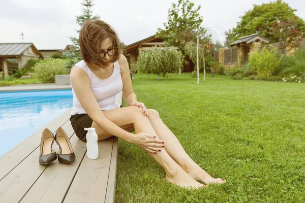 Madura mujer de negocios después de una jornada de trabajo se sienta cerca de la piscina de la casa. Ella se quitó los zapatos y untó sus pies con crema para los pies . —  Fotos de Stock