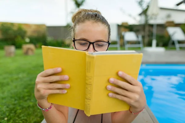 小女孩戴着眼镜 在水池边上堆着书 — 图库照片