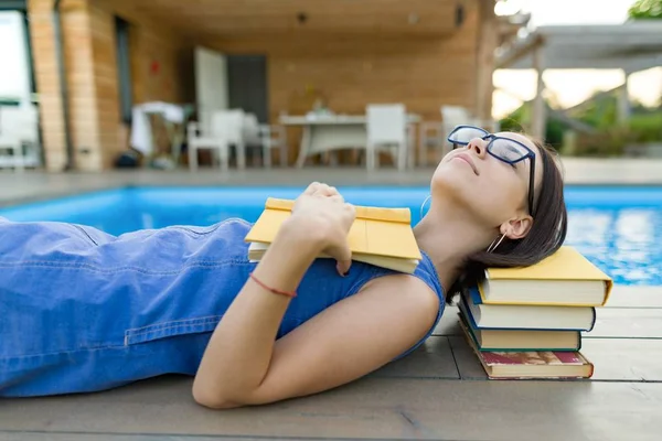 Νεαρό Κορίτσι Γυαλιά Κοντά Στην Πισίνα Ένα Σωρό Βιβλία Ανάγνωση — Φωτογραφία Αρχείου