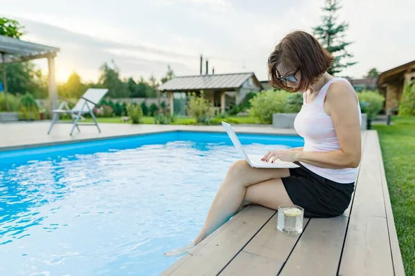 Ώριμη Γυναίκα Freelancer Χρησιμοποιεί Ένα Laptop Κάθεται Δίπλα Στην Πισίνα — Φωτογραφία Αρχείου