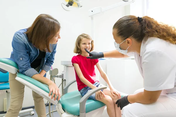 Mor och lilla dotter besöker tandläkare vid tandvårdskliniker. Ortodontist sätter på, korrigerar dental plattan på barnet — Stockfoto