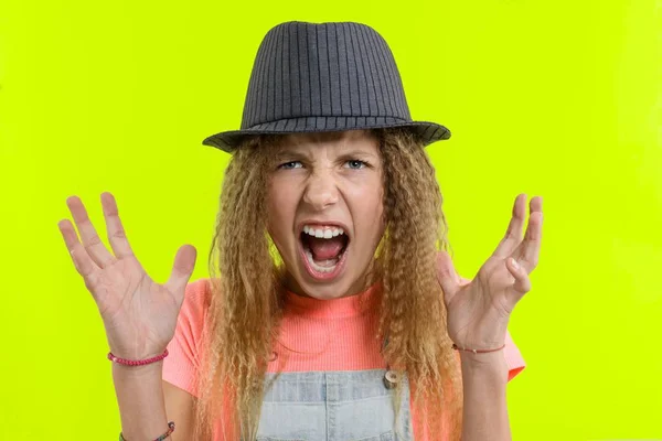 Portrait of an aggressive screaming teen girl over yellow studio background — Stok Foto