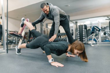 Genç kadın spor salonunda kişisel eğitmen ile yapıyor. Spor, sporcu, eğitim, sağlıklı yaşam ve insan kavramı