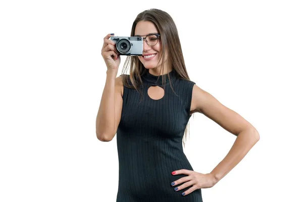 Giovane bella donna sorridente in occhiali da sera che tiene la macchina fotografica tra le mani, scattando foto, su sfondo bianco isolato — Foto Stock