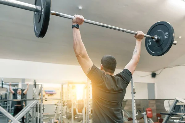 Muskulöser junger Mann, der im Fitnessstudio mit Langhantel-Gewichten arbeitet. Sport, Bodybuilding, Athlet, Gewichtheben, Trainingskonzept — Stockfoto