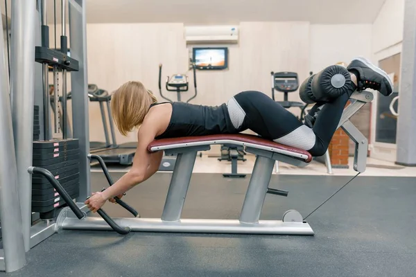Mujer atlética joven haciendo ejercicios en las piernas y las nalgas en el gimnasio. Deporte, fitness, culturismo, entrenamiento, concepto de estilo de vida saludable — Foto de Stock