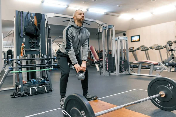 Adult handsome bearded man doing physical exercises in the gym. Sport rehabilitation, age, healthy lifestyle concept.