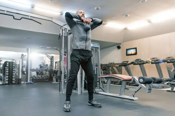 Adult handsome bearded man doing physical exercises in the gym. Sport rehabilitation, age, healthy lifestyle concept.