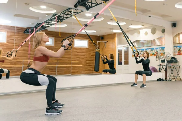 Due donne che fanno allenamento di gruppo con cinghie fitness in palestra. Sport, fitness, allenamento, stile di vita sano . — Foto Stock