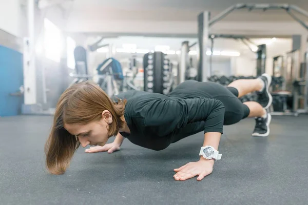 Giovane donna fitness che lavora fuori facendo flessioni sul pavimento in palestra sportiva. Sport, fitness, allenamento, stile di vita e concetto di persone — Foto Stock