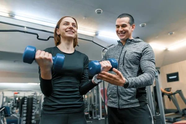 Mężczyzna osobisty trener fitness pomaga młoda kobieta robić trening na siłowni. Sport, sportowiec, szkolenia, zdrowego stylu życia i koncepcja ludzie — Zdjęcie stockowe