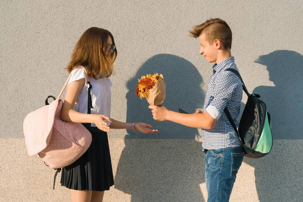 Αγόρι δίνει κορίτσι μπουκέτο λουλούδια. Πορτραίτου ζευγάρι εφήβων — Φωτογραφία Αρχείου