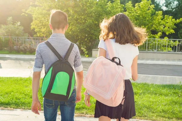 Niños adolescentes van a la escuela, vista trasera. Al aire libre, adolescentes con mochilas — Foto de Stock