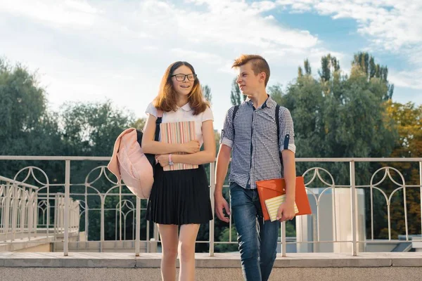 Dospívající studenty s batohy, učebnice, jít do školy. Venkovní portrét dospívající chlapec a dívka 14, 15 let — Stock fotografie