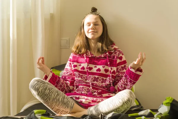 Dospívající dívka meditaci a usmíval se při posezení v józe pozice na posteli — Stock fotografie
