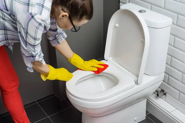 House tisztítás. Nő takarítás WC, női alkalmi ruha mosó-és tisztítószer és mosogatórongy otthon a fürdőszobában — Stock Fotó