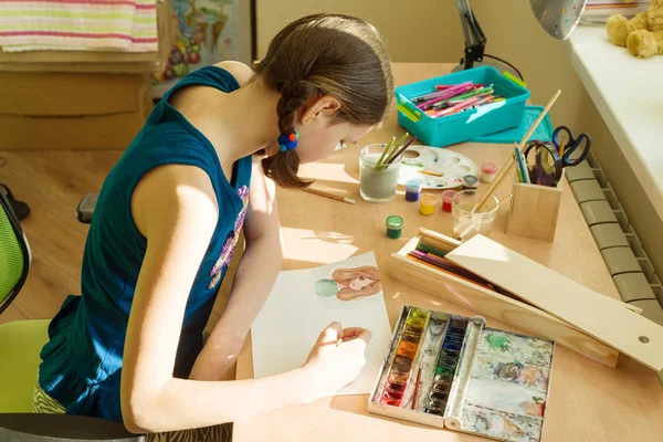 La muchacha adolescente en casa se ocupa de la obra, dibuja la acuarela a la mesa en la habitación — Foto de Stock