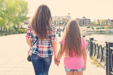 Anne ve kızı arkadan görünüm Park'ta yürüyordunuz elele