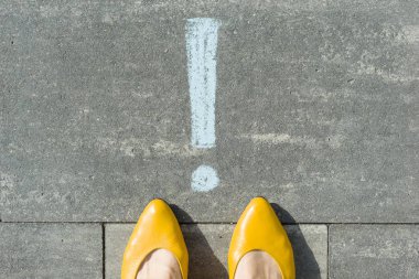 Ünlem işareti simgesi asfalt üzerine çizilmiş dikkat kadın ayakları