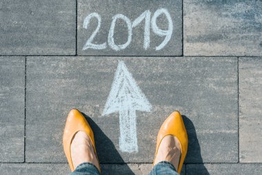 Kadın ayakları ile ok ve metin asfalt üzerinde yazılı 2019