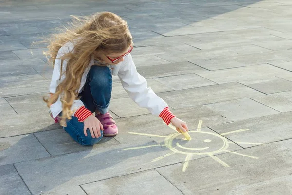 Niño niña dibuja el símbolo del sol con crayones de colores en el asfalto — Foto de Stock