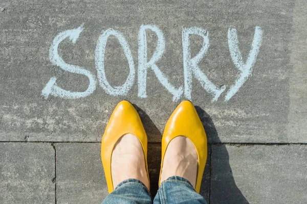 Pés femininos com texto desculpe escrito no asfalto — Fotografia de Stock