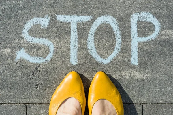A szöveges stop írt aszfalt női láb — Stock Fotó