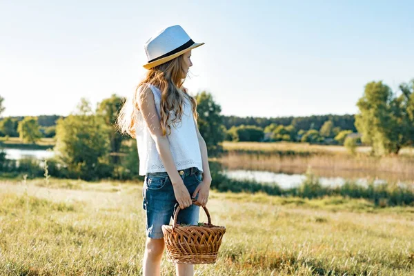 Venkovní letní portrét holčička s košík jahod, slaměný klobouk. Přírodní pozadí, venkovské krajiny, zelená louka, stylu country — Stock fotografie