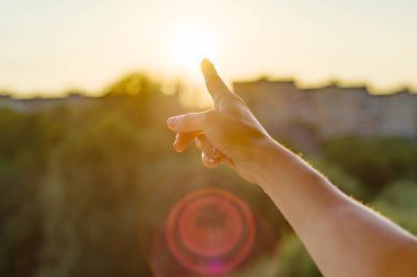 Gün batımına doğru işaret parmağı ile jest. Arka plan gökyüzü, şehir, gün batımı silüeti
