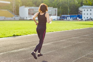 Şişe su stadyumda ile akşam çalışan orta yaşlı kadın portresi. Kopya alanı