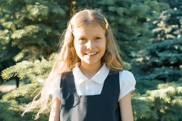 Retrato al aire libre de una pequeña hermosa colegiala sonriente rubia con pelo rizado largo en uniforme escolar —  Fotos de Stock