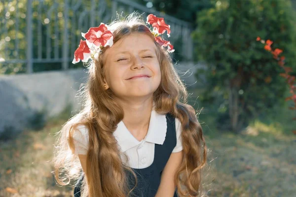 Retrato al aire libre de niña sonriente en guirnalda de flores rosadas con los ojos cerrados, niña con el pelo ondulado largo rubio — Foto de Stock