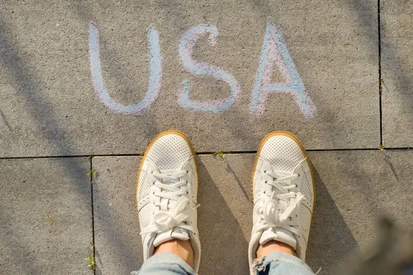 View from above, female feet with text USA written on grey sidewalk — Stock Photo, Image