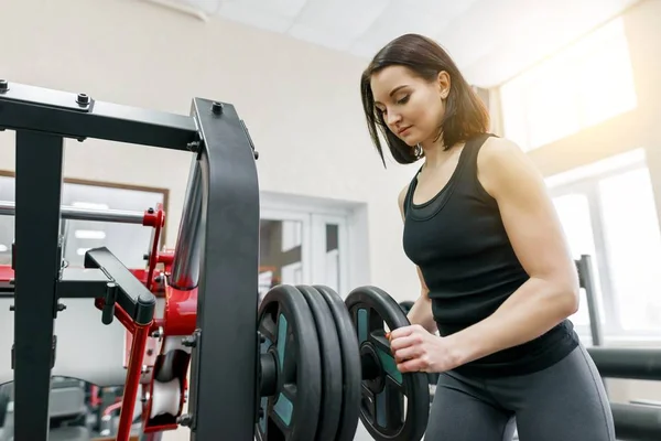 Fiatal, gyönyörű sportos nő barna fitness gyakorlatok az edzőteremben csinál. Fitness, sport, képzés, emberek, egészséges életmód fogalma. — Stock Fotó