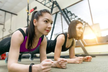 İki fitness kadınlar tahta spor salonunda ayakta. Fitness, spor, eğitim, insanlar, sağlıklı yaşam konsepti.