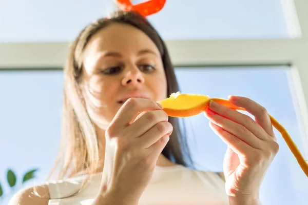 Молода щаслива красива жінка їсть апельсиновий шматочок вдома біля вікна — стокове фото